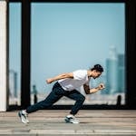 Dynamic shot of a young man sprinting outdoors in an urban setting with skyscrapers in the background.