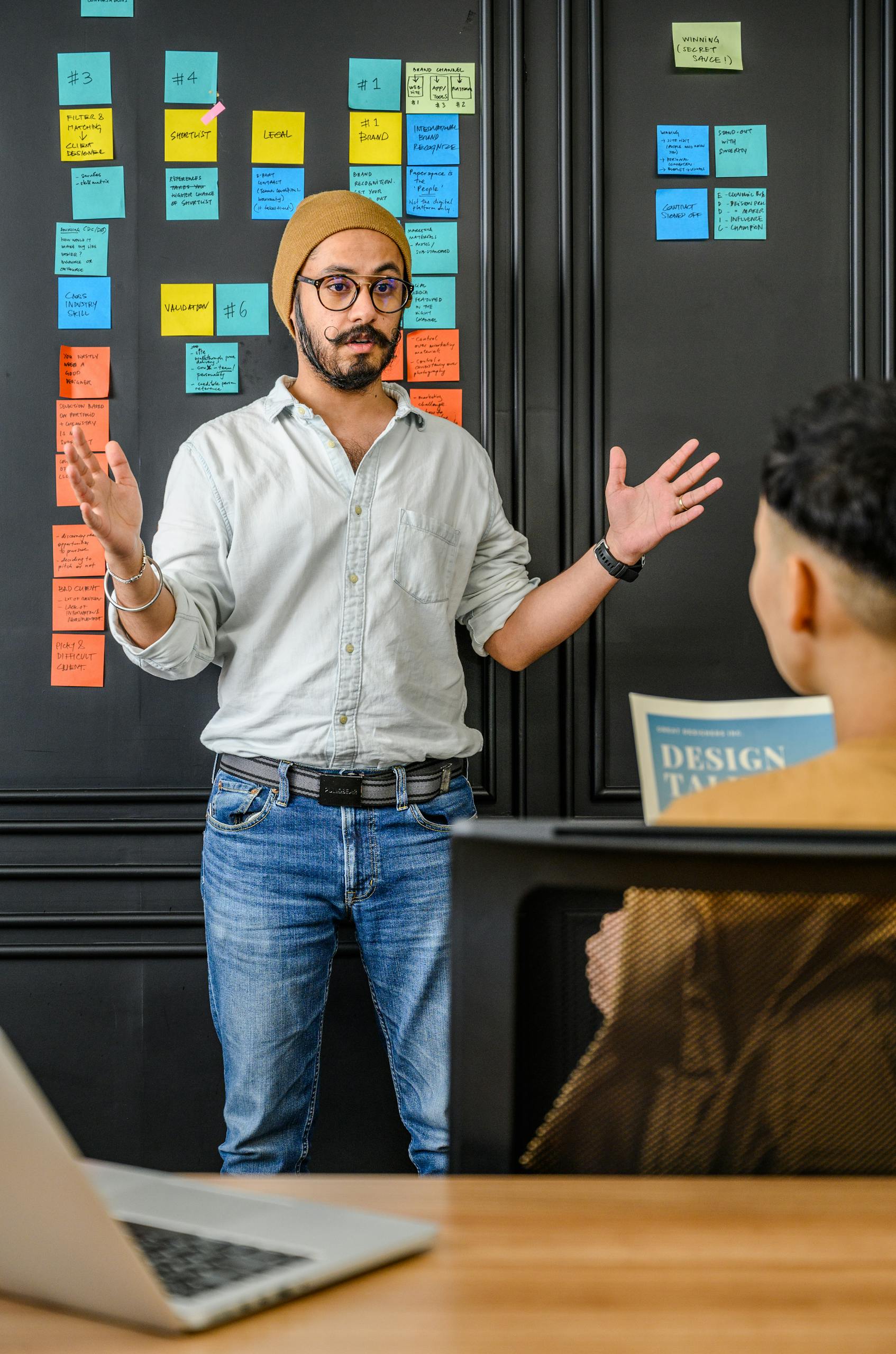 A bearded man discussing ideas with colleagues in an office setting.