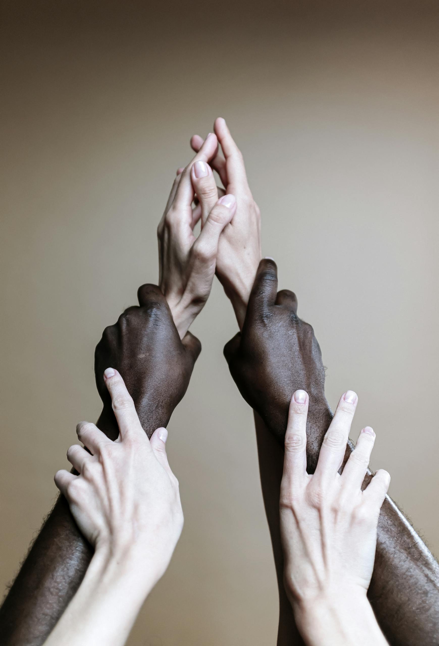 Multiple hands of different ethnicities reaching up, symbolizing unity and togetherness.