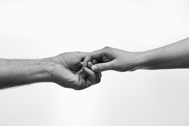 Black and white photo of two hands connecting, symbolizing unity and support.